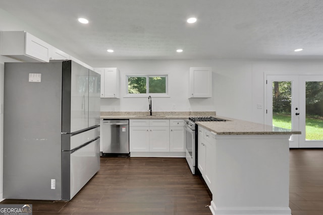 kitchen featuring light stone counters, dark hardwood / wood-style floors, appliances with stainless steel finishes, white cabinets, and sink