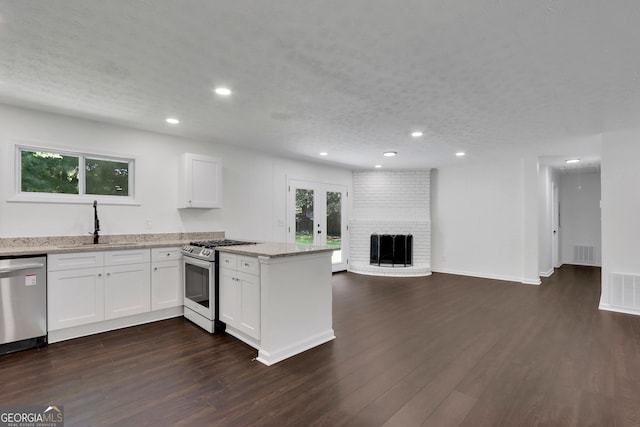 kitchen featuring a fireplace, dark wood-type flooring, stainless steel appliances, and brick wall