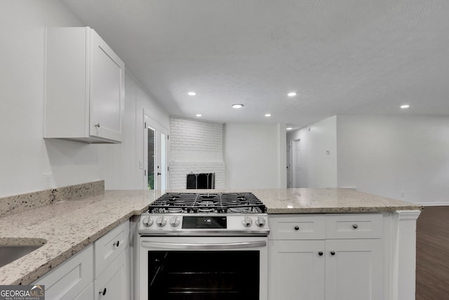 kitchen with kitchen peninsula, white cabinets, hardwood / wood-style flooring, and stainless steel range with gas cooktop