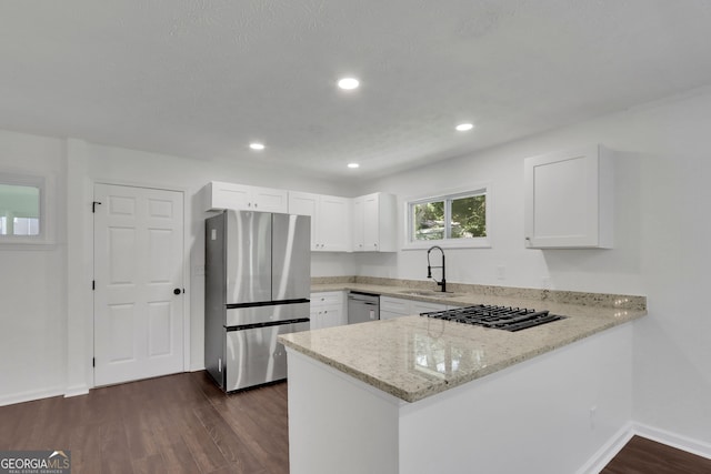 kitchen with dark hardwood / wood-style flooring, stainless steel appliances, light stone countertops, white cabinetry, and sink