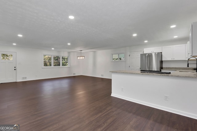 kitchen featuring stainless steel fridge, white cabinets, light stone counters, and hardwood / wood-style flooring