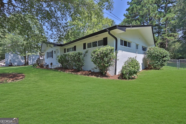 view of side of home featuring a yard, fence, and brick siding