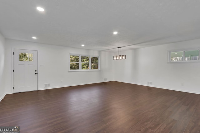 unfurnished living room with hardwood / wood-style floors and an inviting chandelier