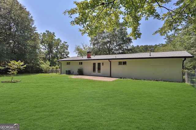 rear view of house featuring central air condition unit, a lawn, a patio, and french doors