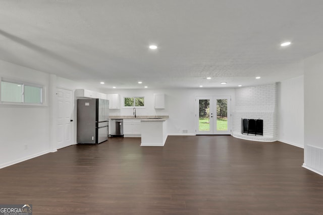 unfurnished living room featuring a brick fireplace, dark hardwood / wood-style flooring, and a wealth of natural light