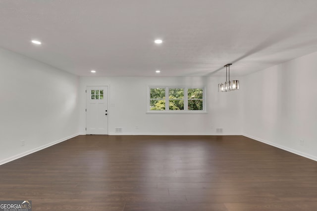 unfurnished living room featuring dark hardwood / wood-style flooring and a chandelier