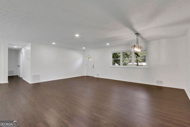 unfurnished living room with a notable chandelier and dark hardwood / wood-style flooring