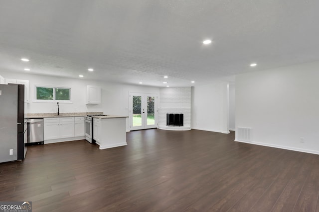 unfurnished living room featuring a fireplace, dark wood-type flooring, sink, and brick wall