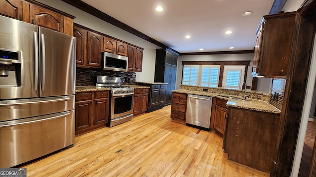 kitchen featuring stainless steel appliances, decorative backsplash, light stone countertops, sink, and light hardwood / wood-style floors