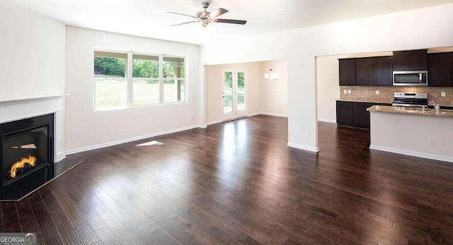 unfurnished living room featuring dark hardwood / wood-style floors, sink, and ceiling fan