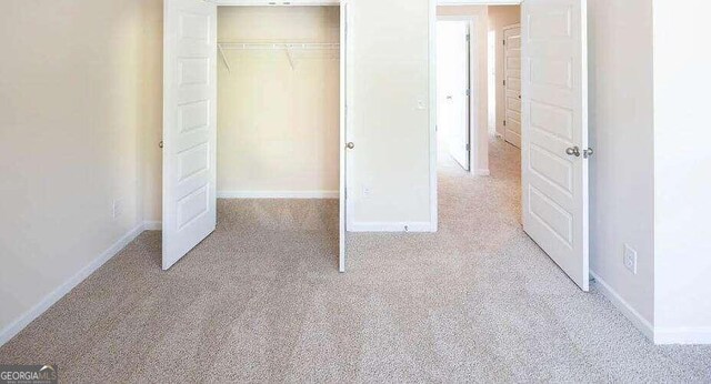 unfurnished bedroom with light carpet and a closet