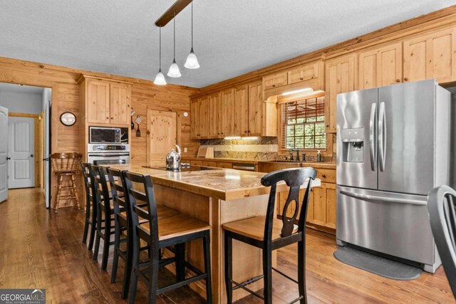 225 Big Oconee River Rd, Sparta, GA 31087 - kitchen with light brown cabinets, wooden walls, stainless steel appliances, dark wood-style flooring, and a kitchen breakfast bar