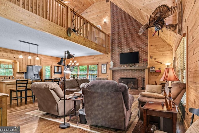 225 Big Oconee River Rd, Sparta, GA 31087 - living area featuring wood walls, a brick fireplace, wood finished floors, and an inviting chandelier