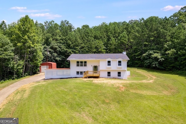 raised ranch with a front yard, a garage, an outbuilding, and a wooden deck