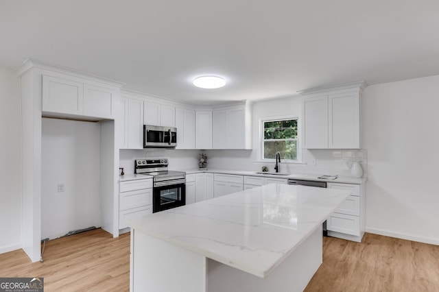 kitchen featuring stainless steel appliances, light hardwood / wood-style floors, white cabinets, sink, and a kitchen island