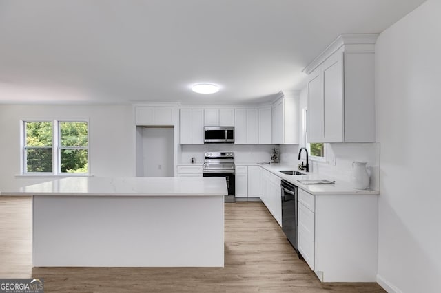 kitchen with appliances with stainless steel finishes, light wood-type flooring, and white cabinetry