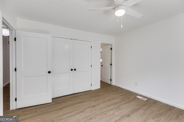 unfurnished bedroom featuring ceiling fan, light wood-type flooring, and a closet