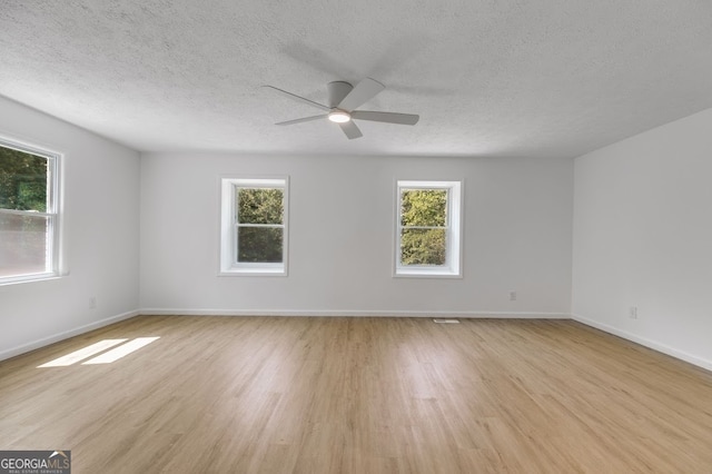 empty room featuring ceiling fan, light hardwood / wood-style flooring, and a healthy amount of sunlight