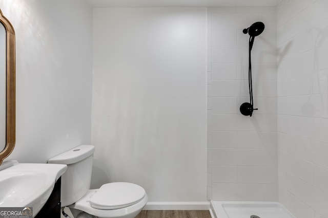 bathroom featuring vanity, toilet, a tile shower, and hardwood / wood-style flooring