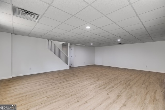 basement with a drop ceiling and light hardwood / wood-style floors