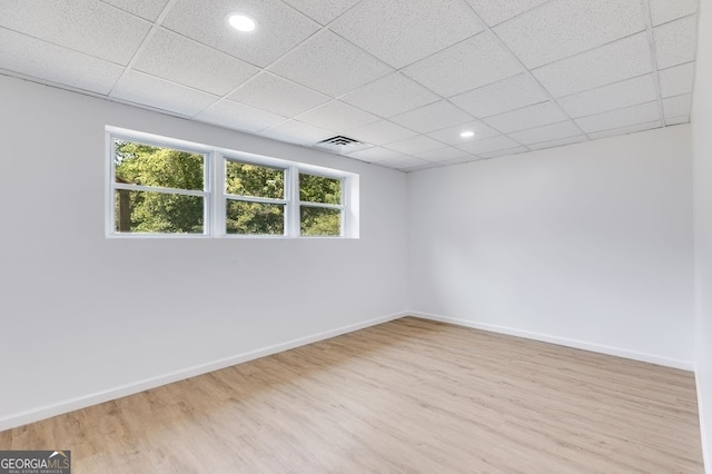 spare room featuring a drop ceiling and light hardwood / wood-style floors