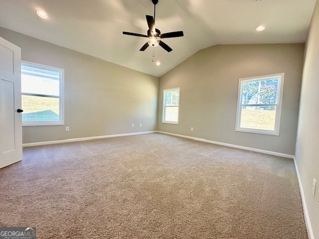 carpeted empty room with ceiling fan, lofted ceiling, and plenty of natural light