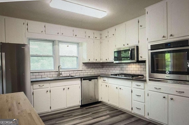 kitchen featuring appliances with stainless steel finishes, sink, backsplash, dark hardwood / wood-style flooring, and white cabinets