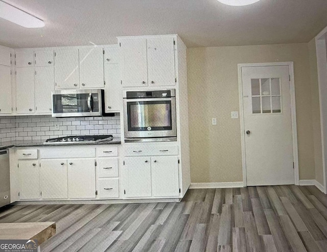 kitchen featuring appliances with stainless steel finishes, dark hardwood / wood-style floors, white cabinetry, and tasteful backsplash