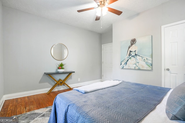 bedroom with a textured ceiling, hardwood / wood-style flooring, and ceiling fan