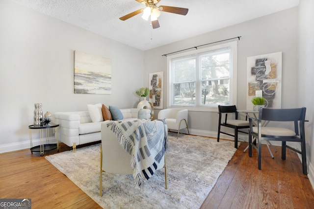 living room featuring a textured ceiling, hardwood / wood-style floors, and ceiling fan