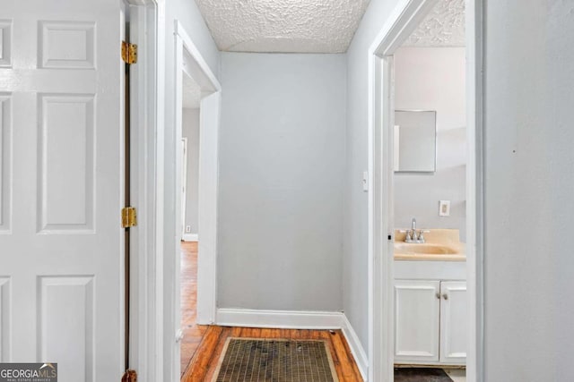 hallway featuring hardwood / wood-style flooring, sink, and a textured ceiling