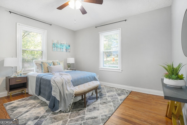 bedroom featuring hardwood / wood-style floors, ceiling fan, and a textured ceiling