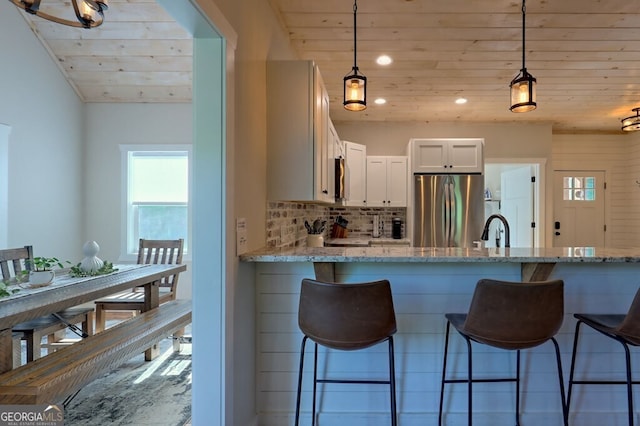 kitchen with appliances with stainless steel finishes, tasteful backsplash, white cabinets, and light stone countertops