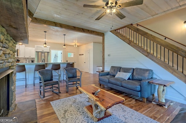 living room with wooden ceiling, a ceiling fan, light wood-style floors, stairway, and beam ceiling