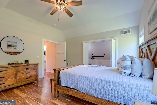 bedroom with dark wood-style floors, visible vents, vaulted ceiling, and a ceiling fan