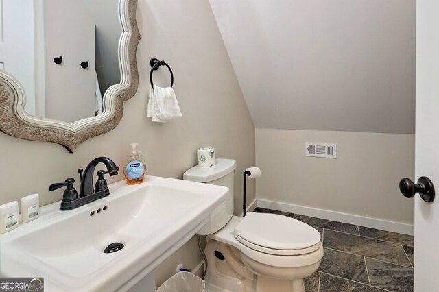 bathroom featuring sink, vaulted ceiling, tile patterned flooring, and toilet