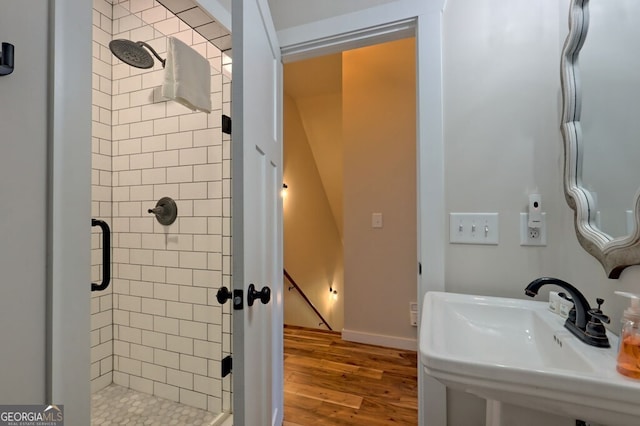 bathroom featuring a shower with shower door, sink, and wood-type flooring