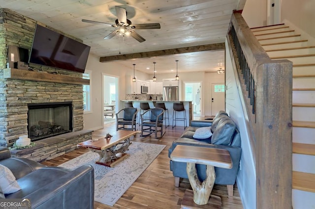 living room with a fireplace, hardwood / wood-style floors, ceiling fan, and a healthy amount of sunlight