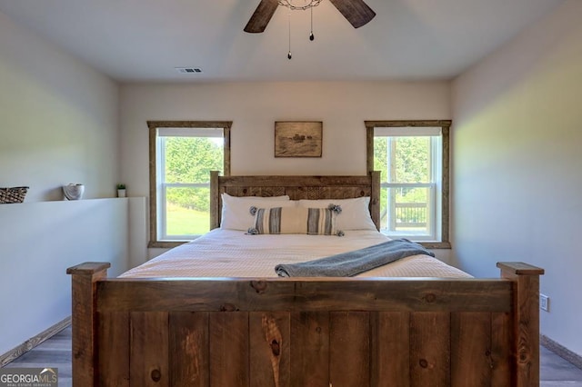 bedroom with a ceiling fan, visible vents, and dark wood-style flooring