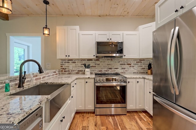 kitchen with stainless steel appliances, white cabinetry, decorative light fixtures, and light stone countertops