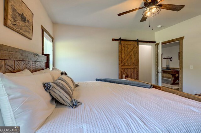 bedroom featuring ceiling fan and a barn door