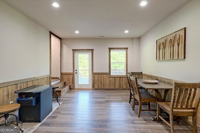 dining room with a wainscoted wall, wooden walls, wood finished floors, and recessed lighting