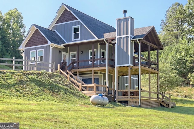 back of property with a chimney, roof with shingles, fence, a yard, and board and batten siding