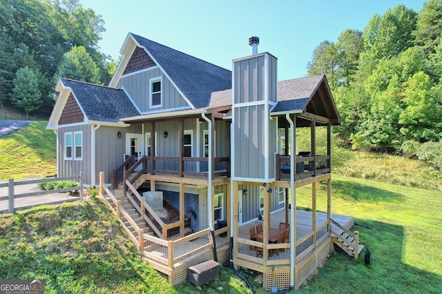 rear view of house with a chimney, a lawn, board and batten siding, and roof with shingles