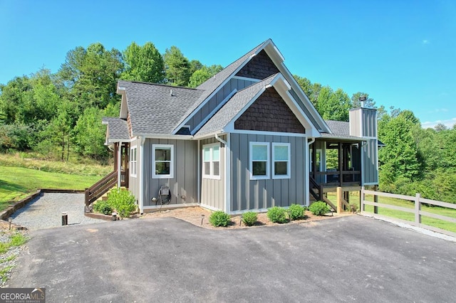 view of front of house featuring a sunroom, a shingled roof, stairs, and board and batten siding