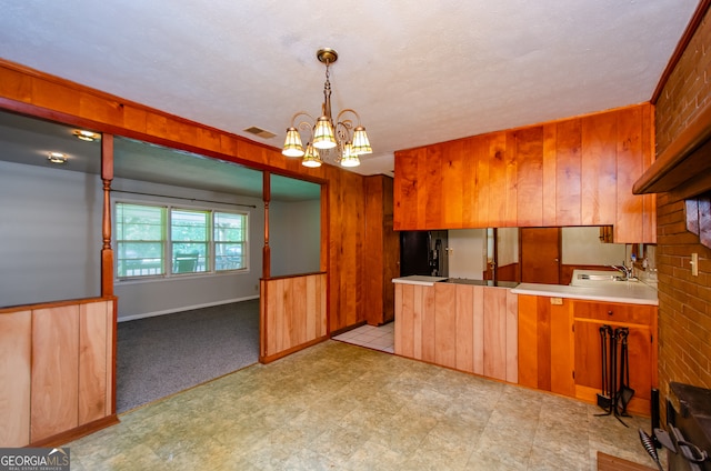 kitchen featuring pendant lighting, a notable chandelier, light tile patterned flooring, black fridge, and kitchen peninsula