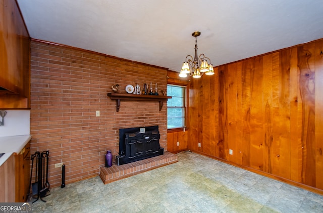 unfurnished living room with light tile patterned flooring, wood walls, a wood stove, a chandelier, and brick wall