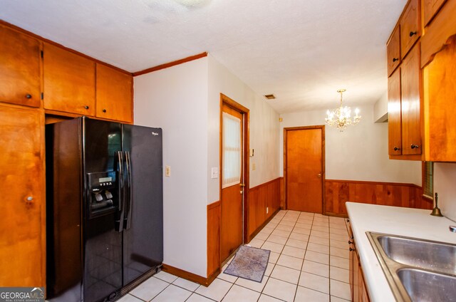 kitchen featuring pendant lighting, light tile patterned flooring, sink, a chandelier, and black fridge