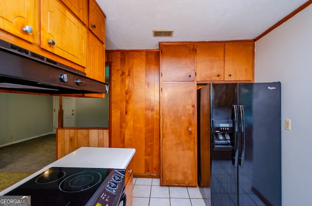 kitchen featuring light tile patterned floors, a textured ceiling, black fridge, and range