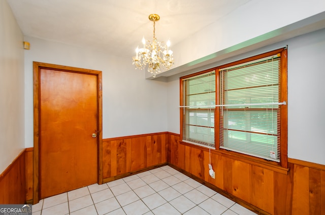 tiled spare room with an inviting chandelier